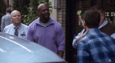 A Man In A Purple Sweater Is Standing In Front Of A Sign That Says " E De " GIF