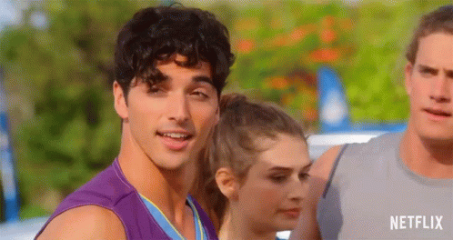 A Man In A Purple Tank Top Is Smiling While Standing Next To A Woman And A Man . GIF