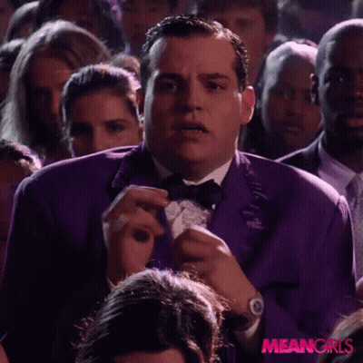 A Man In A Purple Tuxedo And Bow Tie Is In A Crowd Of People . GIF