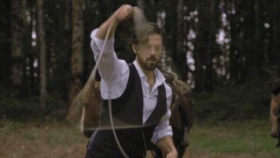A Man In A Purple Vest Is Lassoing A Small Black Calf GIF