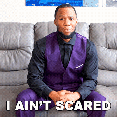 A Man In A Purple Vest Is Sitting On A Couch With The Words I Ain 'T Scared GIF