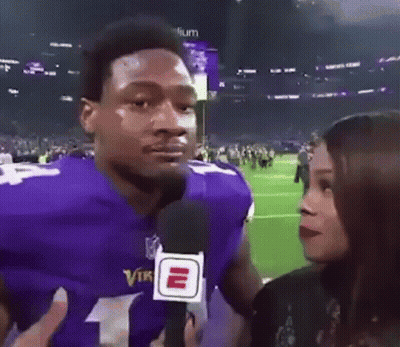 A Man In A Purple Vikings Jersey Is Being Interviewed By A Woman Holding A Microphone . GIF
