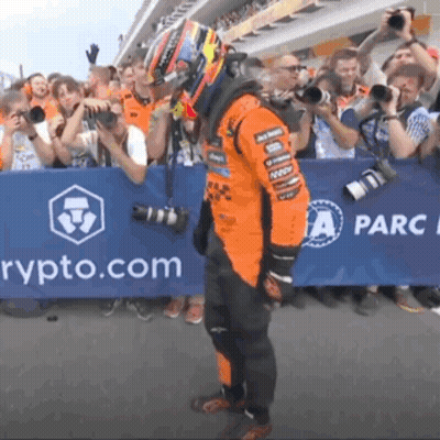 A Man In A Race Suit Is Standing In Front Of A Sign That Says " Rypto.com " GIF