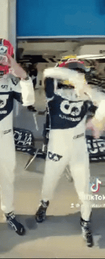 A Man In A Racing Suit Is Dancing With Another Man In A Racing Suit . GIF