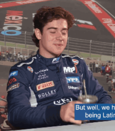 A Man In A Racing Suit Is Drinking From A Cup With The Words But Well We 'Re Being Latin GIF