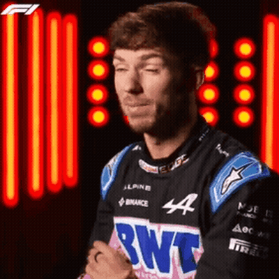 A Man In A Racing Suit Is Standing In Front Of A Neon Light . GIF