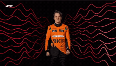 A Man In A Racing Suit Is Standing In Front Of A Red And Black Background . GIF