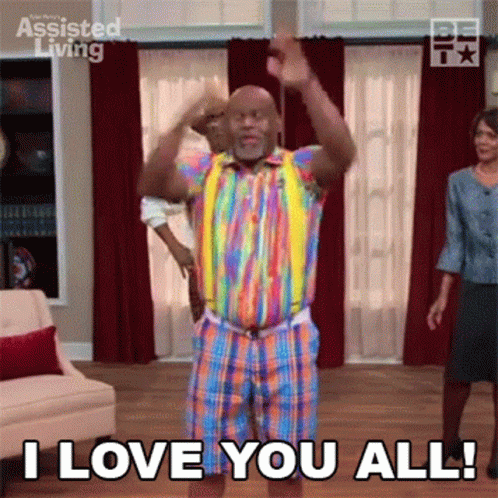 A Man In A Rainbow Shirt And Shorts Is Dancing In A Living Room While A Woman Stands Behind Him . GIF