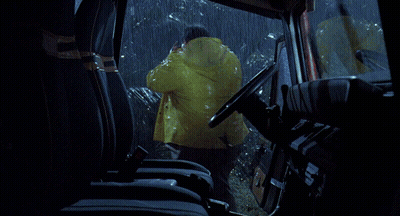 A Man In A Raincoat Is Driving A Car GIF