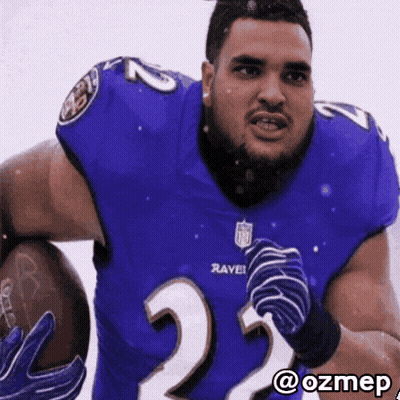 A Man In A Ravens Jersey Holds A Football In His Hands GIF
