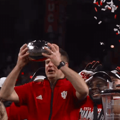 A Man In A Red Adidas Shirt Holds A Trophy In His Hands GIF