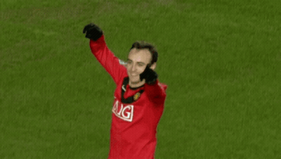 A Man In A Red Aig Jersey Stands On A Green Field GIF