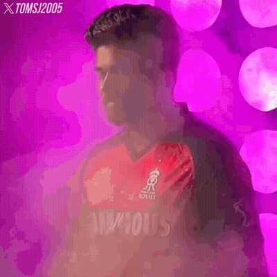 A Man In A Red And Black Cricket Jersey Is Standing In Front Of A Pink Background . GIF