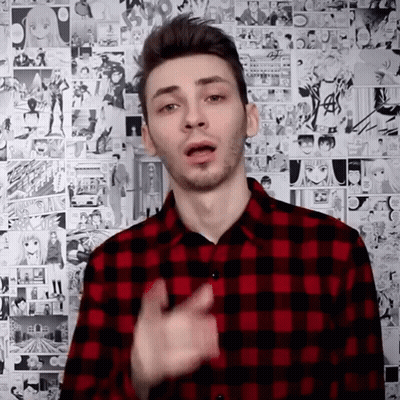 A Man In A Red And Black Plaid Shirt Is Standing In Front Of A Wall Of Comic Strips . GIF