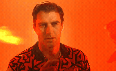 A Man In A Red And Black Shirt Is Standing In Front Of An Orange Background . GIF