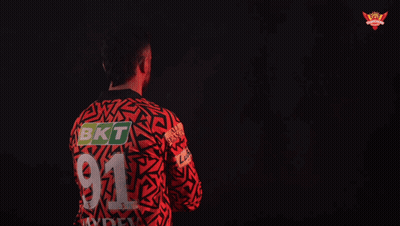 A Man In A Red And Black Shirt With The Name Howzzat GIF