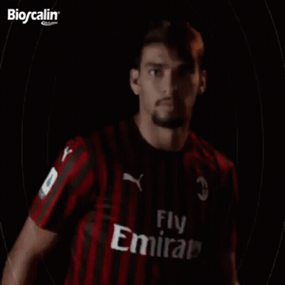 A Man In A Red And Black Striped Shirt Is Standing In Front Of A Black Background With The Word Paqueta Written On It . GIF
