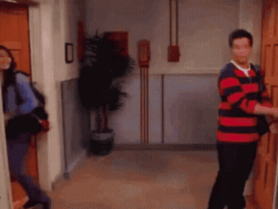 A Man In A Red And Blue Striped Shirt Is Opening A Door For A Woman GIF