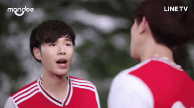 A Man In A Red And White Jersey Is Talking To Another Man In A Line Tv Ad GIF