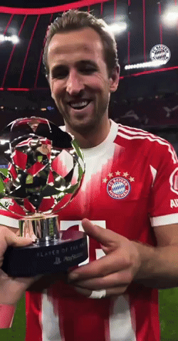 A Man In A Red And White Striped Jersey Holds A Trophy GIF