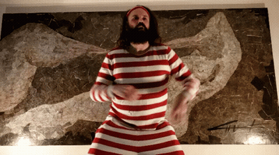 A Man In A Red And White Striped Shirt Is Dancing In Front Of A Painting GIF