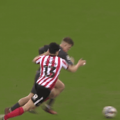 A Man In A Red And White Striped Shirt Is Hugging Another Man In A Black Shirt On A Soccer Field . GIF