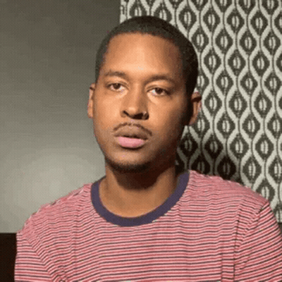 A Man In A Red And White Striped Shirt Is Making A Face . GIF