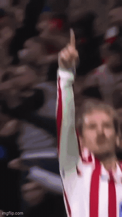 A Man In A Red And White Striped Shirt Is Raising His Finger Up In The Air GIF