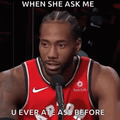 A Man In A Red Basketball Jersey Is Talking Into A Microphone . GIF