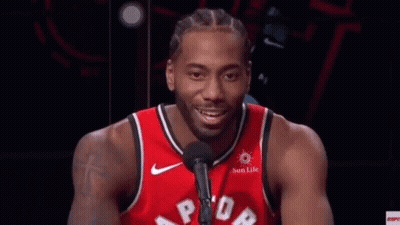 A Man In A Red Basketball Jersey Is Talking Into A Microphone . GIF