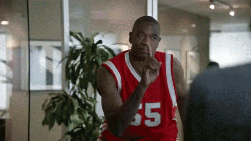 A Man In A Red Basketball Jersey With The Number 35 On It Is Talking To Another Man In A Room . GIF