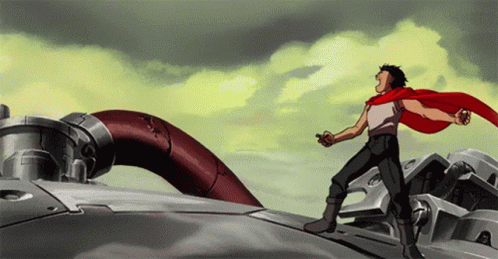 A Man In A Red Cape Is Standing On Top Of A Metal Object GIF