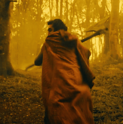 A Man In A Red Cape Walking Through A Forest GIF