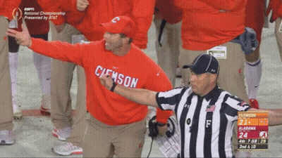 A Man In A Red Clemson Sweatshirt Stands Next To An Umpire GIF