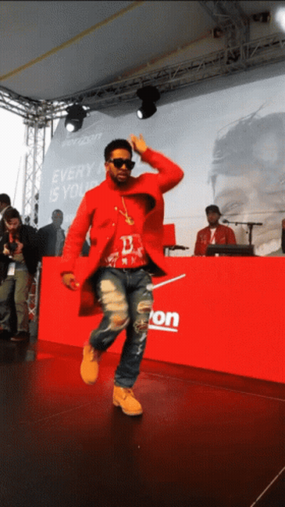 A Man In A Red Coat Is Dancing In Front Of A Verizon Sign GIF