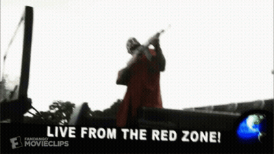 A Man In A Red Coat Is Holding A Gun In Front Of A Car That Says `` We From The Red Zone '' . GIF