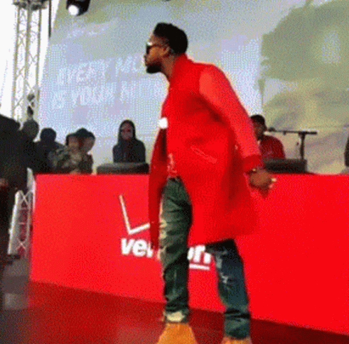 a man in a red coat is standing in front of a red verizon sign