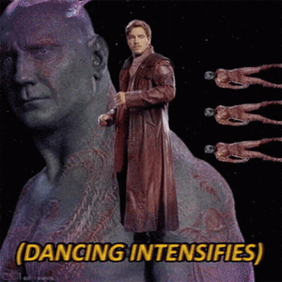 A Man In A Red Coat Is Standing In Front Of A Statue With The Words Dancing Intensifies Below Him GIF