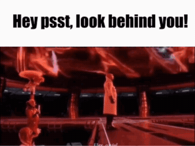 A Man In A Red Coat Is Standing On A Stage In Front Of A Crowd And Says Hey Psst Look Behind You . GIF