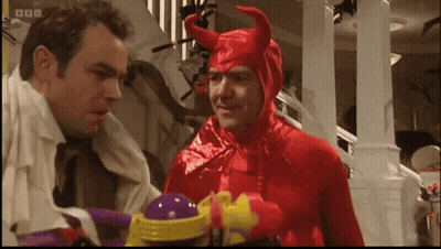 A Man In A Red Devil Costume Talks To Another Man In A White Shirt GIF