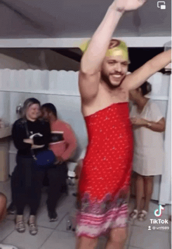 A Man In A Red Dress Is Dancing In Front Of A Group Of People .. GIF
