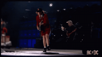 A Man In A Red Dress Is Playing A Guitar On A Stage With Ac/dc Written On The Bottom GIF