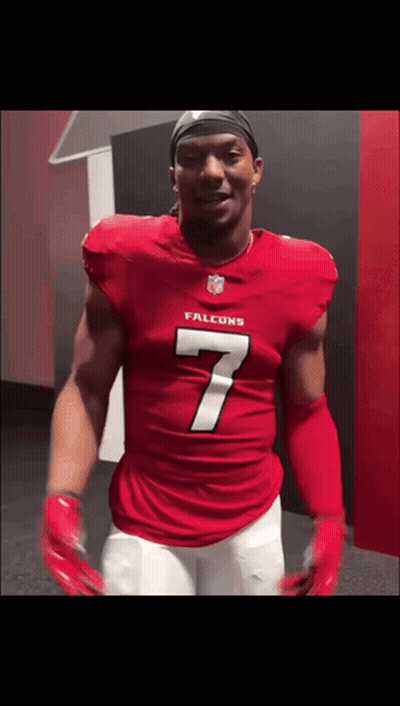 A Man In A Red Falcons Jersey Is Standing In A Locker Room GIF