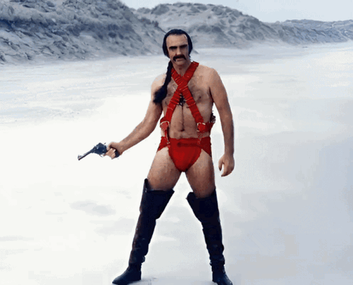 A Man In A Red Harness And Boots Holds A Gun GIF