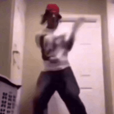 A Man In A Red Hat Is Dancing In A Room With A Laundry Basket Behind Him . GIF