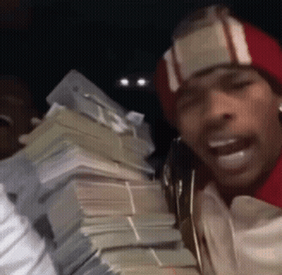 A Man In A Red Hat Is Holding A Large Pile Of Money . GIF