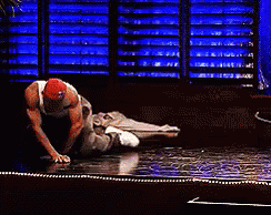 A Man In A Red Hat Is Kneeling On A Stage . GIF
