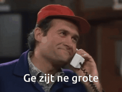 A Man In A Red Hat Is Standing In Front Of A Bar With The Words Ge Zijt Ne Grote Written On The Bottom GIF