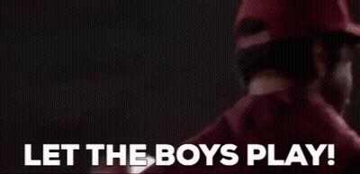 A Man In A Red Hat Is Standing In Front Of A Sign That Says `` Let The Boys Play ! '' GIF