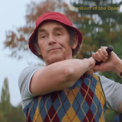 A Man In A Red Hat Is Swinging A Golf Club With The Words Phantom Of The Open Above Him GIF